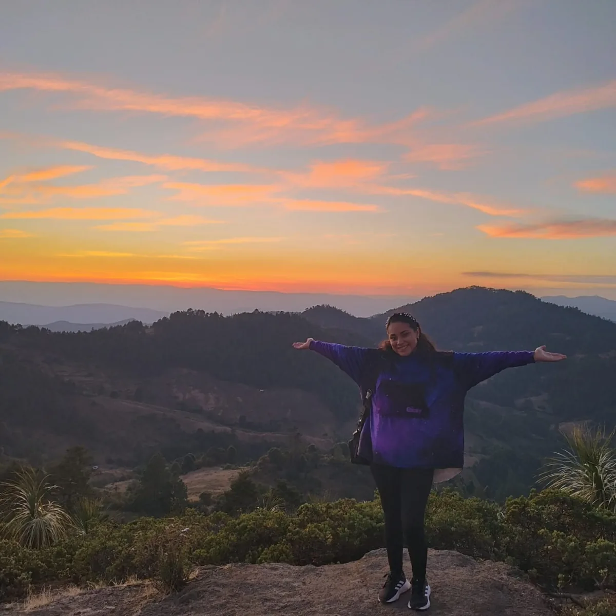 Viajera contemplando las montañas desde un mirador al atardecer